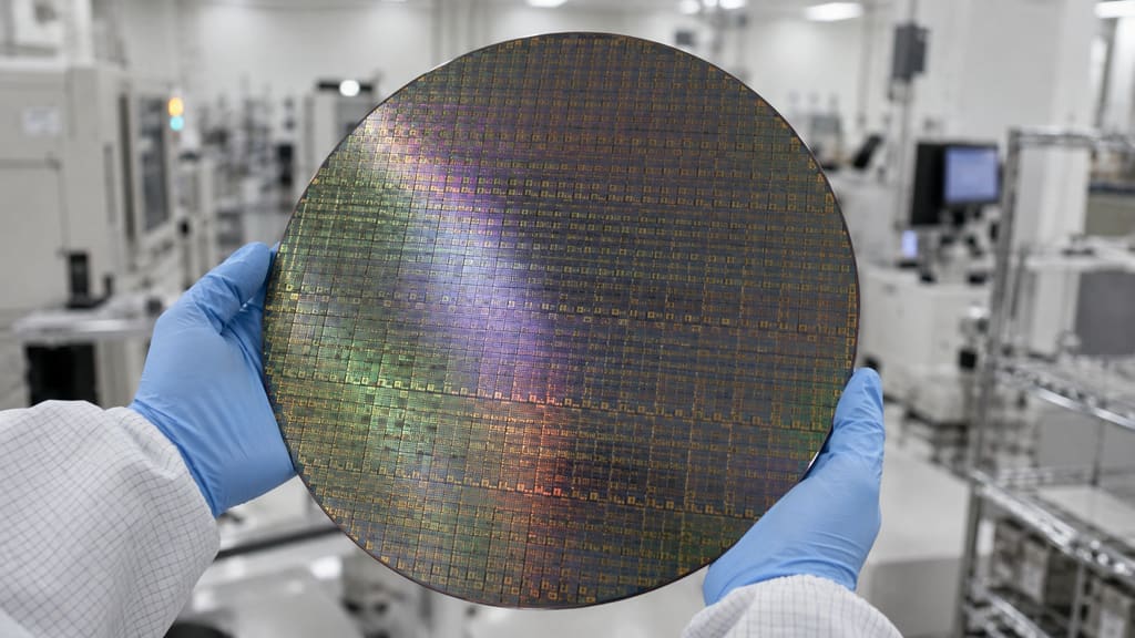 Illustration: a silicon wafer held in gloved hands in a clean room